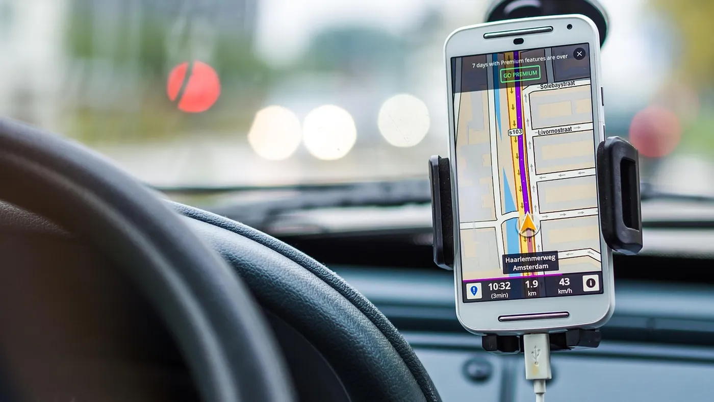 Vue conducteur avec smartphone GPS fixé au tableau de bord, trafic urbain