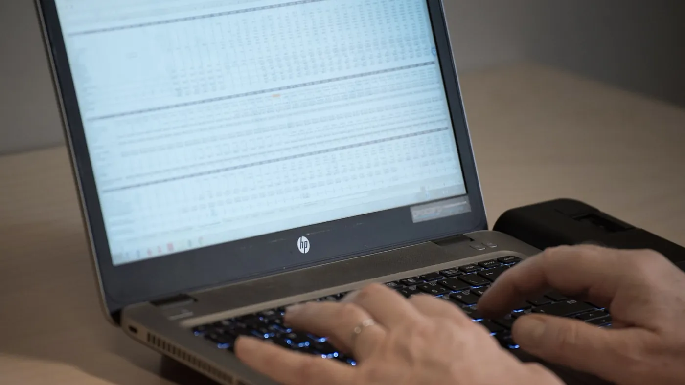 Gestionnaire de flotte VTC assis à son bureau dimanche soir, plusieurs feuilles Excel ouvertes sur l'écran, regardant des chiffres avec une expression concentrée